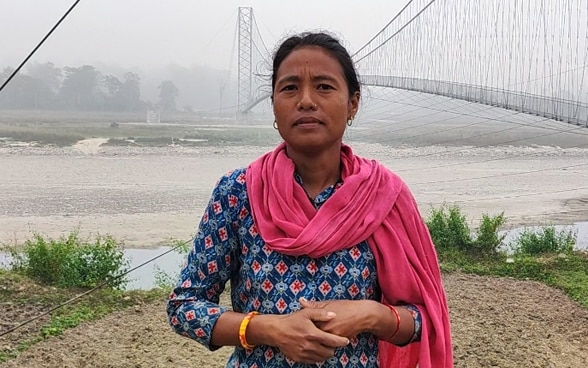 Una mujer mira a la cámara, el puente colgante al fondo.