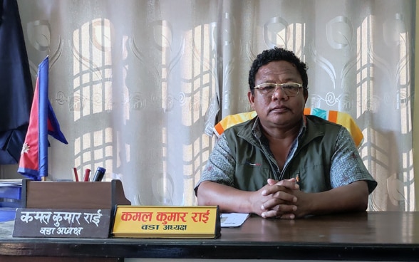 Ein Nepalese sitzt im Büro hinter seinem Schreibtisch.