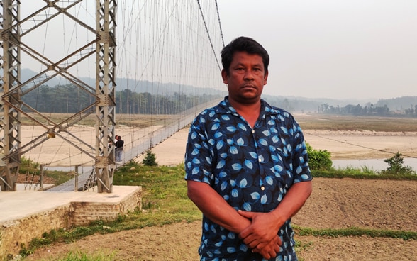 Ein Mann steht vor der Hängebrücke.
