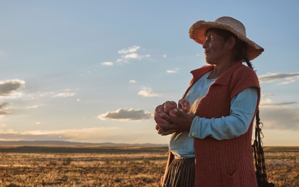 Una campesina boliviana sostiene patatas en sus manos.