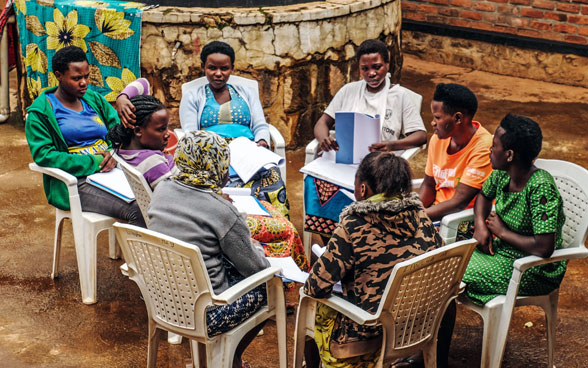 Trabajo en grupo como parte del enfoque comunitario "We Heal Together" en Ruanda. Ocho mujeres sentadas en círculo hablan entre ellas.
