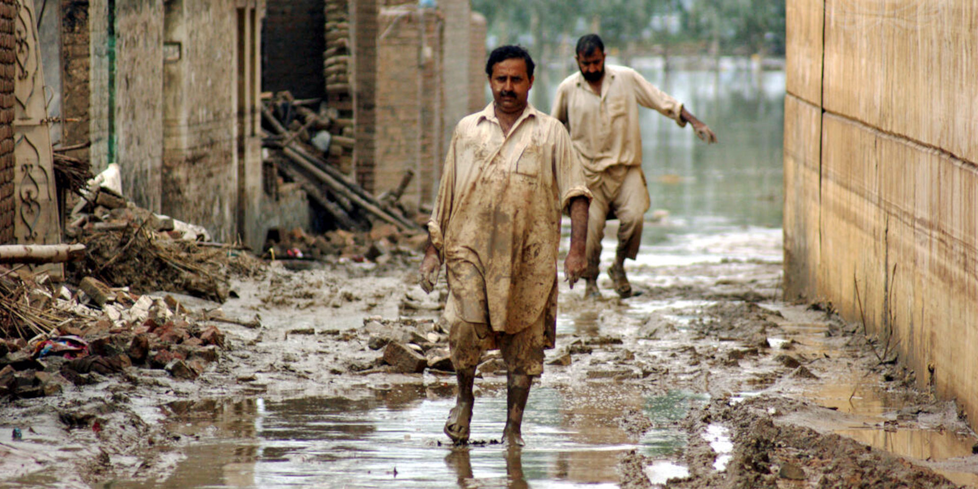 Víctimas de las inundaciones de 2010 en Pakistán caminan por calles llenas de agua en la ciudad noroccidental de Nowshera.