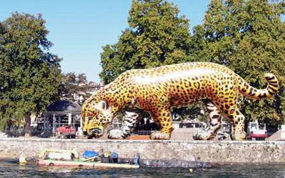 On the Île de Rousseau, Geneva, an oversized inflatable jaguar stands at the water’s edge.