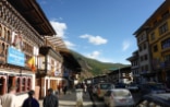 A Swiss visitor walking along a street with two local people in the Bhutanese capital, Thimpu.