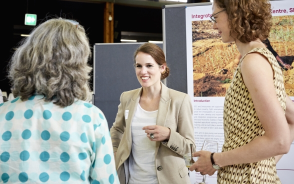 Two participants talking to a stand supervisor for one of the partner organisations. 