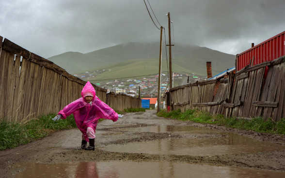 Kind geht im Regen durch eine schlammige Strasse im Jurten-Bezirk von Ulaanbaatar.