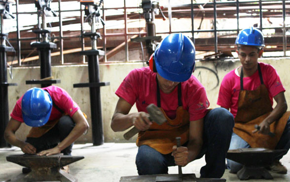 Drei junge Männer arbeiten auf einer Baustelle.