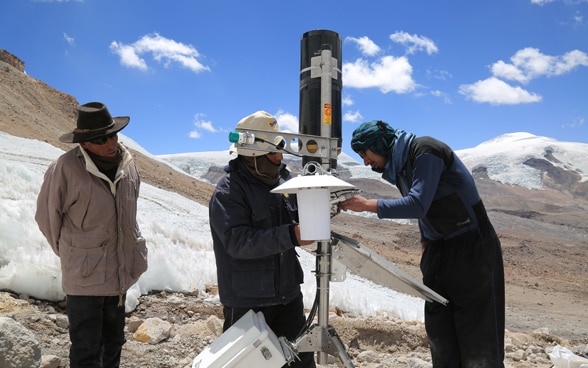 Drei Männer installieren eine automatische Wetterstation im Peruanischen Hochland