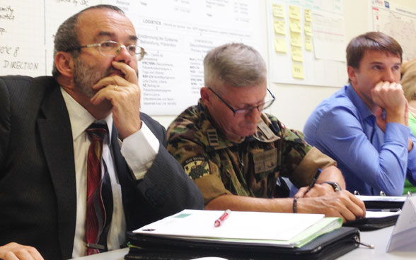 Des représentants de l’armée suisse écoutent attentivement.