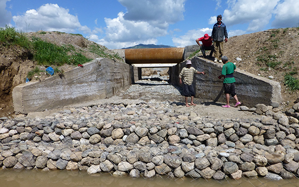 A group of men standing next to the recently built outlet of a drainage canal.