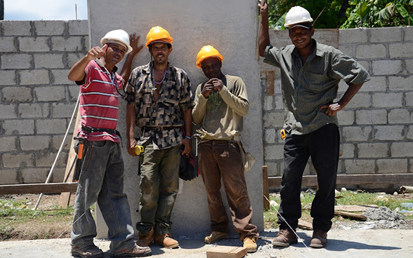 Vier haitianische Bauarbeiter posieren für ein Foto auf der Baustelle. © DEZA