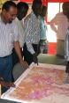 A group of people standing around a table with a map spread over it.