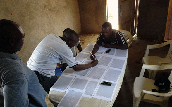 A group of men marking things on a map.