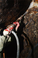 A miner is drilling rock in search of gold