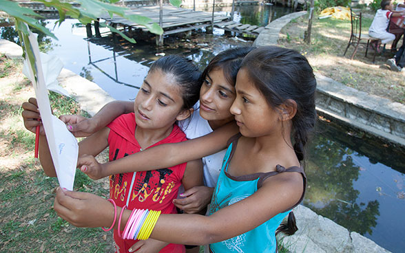 Three girls watching a sketch at summer camp.