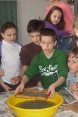 Boys and girls watching a fellow pupil doing an experiment with water.