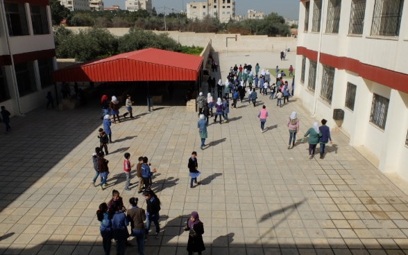Niños y niñas jugando en el patio de una escuela rehabilitada.