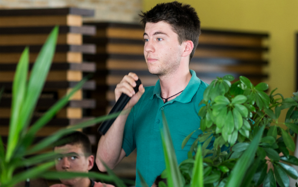 A young man holding a microphone in his hand, listening intently to the discussion.