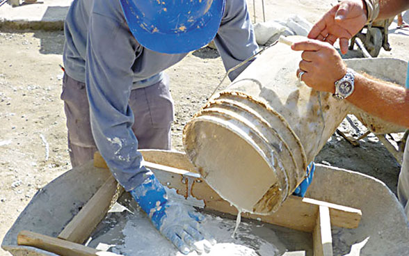Deux ouvriers  coulent du ciment dans un moule en bois.