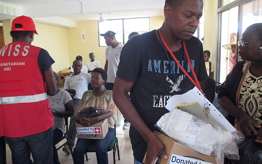 Haitianerinnen und Haitianer erhalten Schachteln mit Hygieneartikeln.