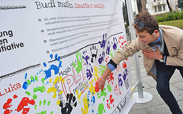 A young man adds his handprint in paint to a collective charter.