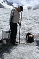 Two men working with specialist equipment on a glacier. 