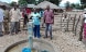 Attorniata da un gruppo di persone, un’abitante di un villaggio nella provincia di Niassa nel Nord del Mozambico aziona una nuova pompa manuale.