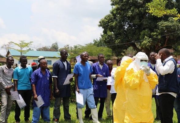 Personale di cura ascolta i consigli di un formatore accompagnato da due persone che indossano vestiti di protezione.  