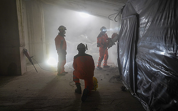 Drei Schweizer Retter, die sich während einer Nachtübung in einem zerstörten Gebäude befinden.