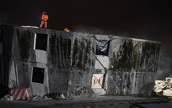 Schweizer Retter, die sich während einer Nachtübung auf einem zerstörten Gebäude befinden.
