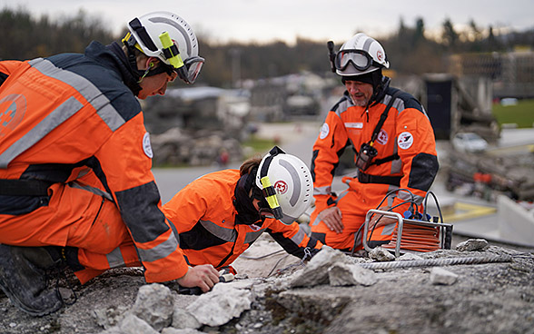 Tre soccorritori svizzeri appostati su un edificio in rovina.
