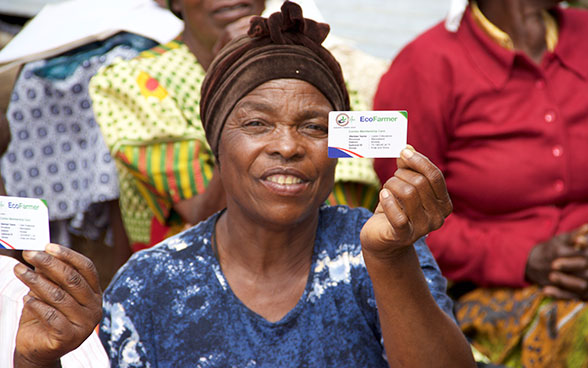 A farmer shows her Eco-Farmer identification card.