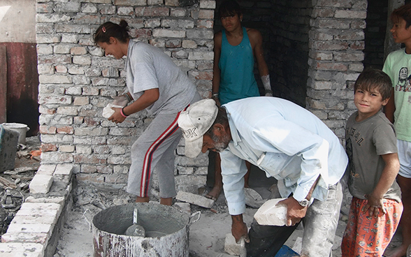 Una famiglia rom costruisce le mura per la sua casa.