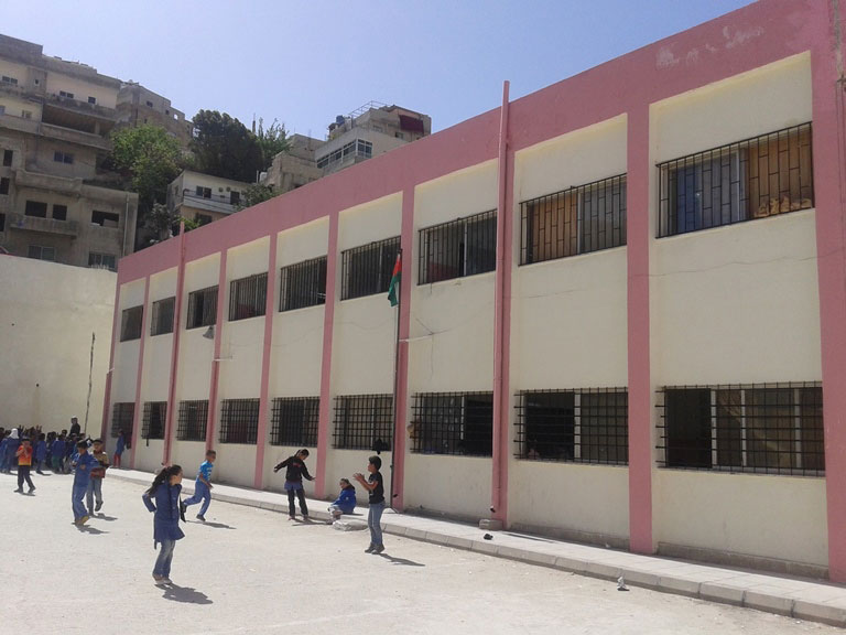 Dei bambini giocano nel piazzale di una scuola giordana ripristinata. 