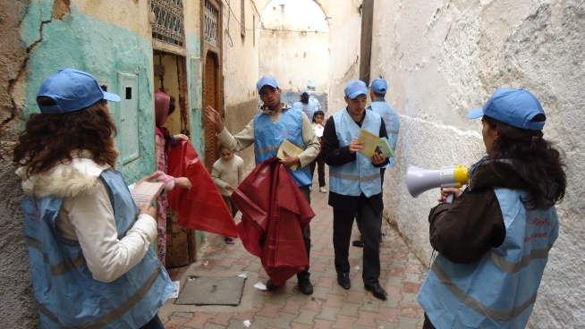 A group of volunteer relief workers distributes information and materials in a street 