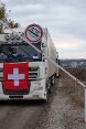 Un soldat lève une barrière, ouvrant la voie à un camion de l’Aide humanitaire suisse.