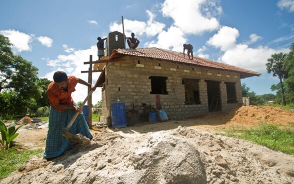 Un Sri-Lankais manie une pelle devant une maison en construction.