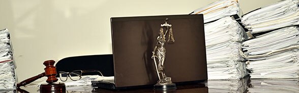 Illustration de l'e-justice: un ordinateur, des piles de dossiers et la statue de la justice