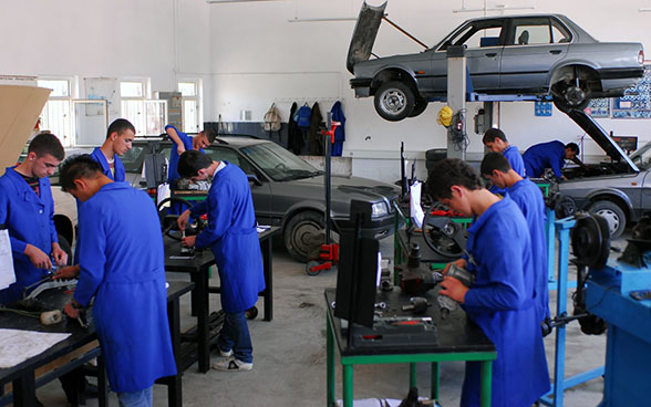 Trainee mechanics repairing cars in a training workshop