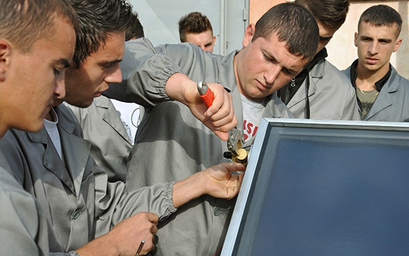 Apprendisti in Albania lavorano su un macchinario termoidraulico.