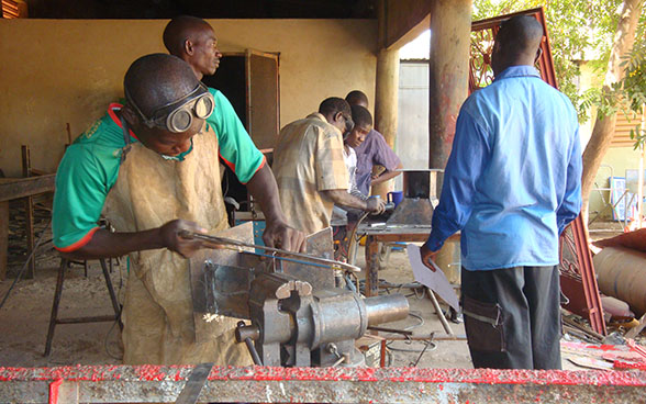 Apprendisti saldatori lavorano in un laboratorio sotto la supervisione di un formatore