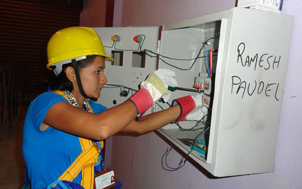 A trainee using a screwdriver on an electric panel