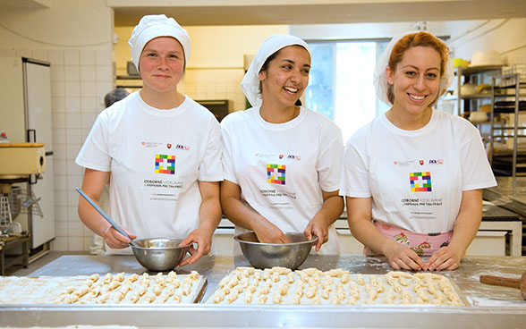 Three apprentice bakers making little croissants