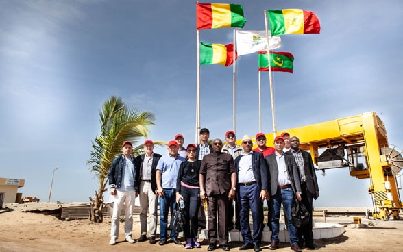 High-level government representatives from Central Asia and West Africa standing in front of a large water pipe. 