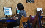 Eine Frau sitzt vor einem Computer und arbeitet mit der Plattform UN CC:Learn.