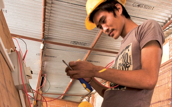 Beschreibung: Drei junge Nepalesen absolvieren eine praktische Elektrikerausbildung.