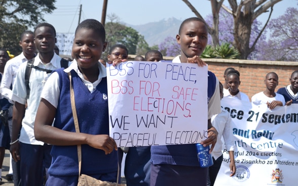Junge Menschen mit Plakaten an einer Kundgebung für Frieden und friedliche Wahlen in Malawi.