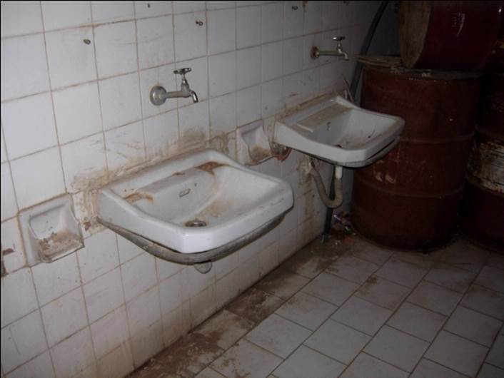 Dos lavabos sucios con los azulejos de las paredes estropeados.