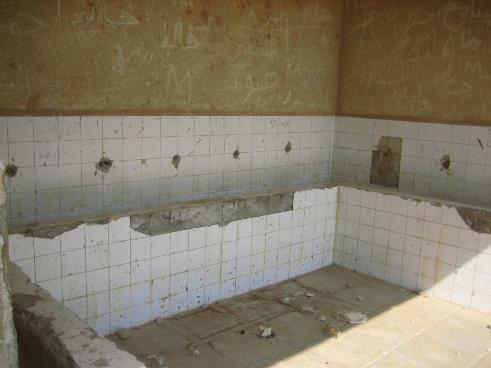Cuarto de baño en el que se han quitado los grifos y los ladrillos están rotos.