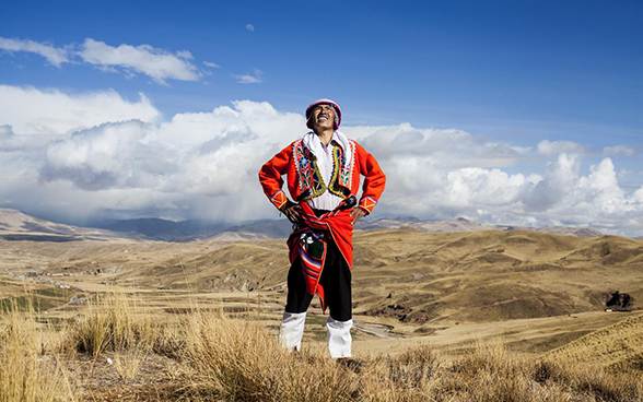 Debout dans les hautes plaines péruviennes, un homme en costume traditionnel observe les phénomènes météorologiques.